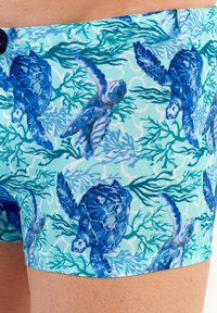 Schwimmshorts in Hellblau mit einem Schildkröten- und Korallenmuster. Das Material ist glatt, elastisch, hat eine enganliegende Passform und einen elastischen Bund.