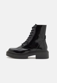 Black patent leather ankle boots with a chunky black sole, featuring lace-up detail and a smooth, glossy finish.