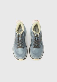 Hellblaue Sportschuhe mit strukturierter Oberseite, akzentuiert durch dunkelgraue Schnürsenkel und Logo. Verfügt über eine gepolsterte Sohle mit orangefarbenem Zuglasche.