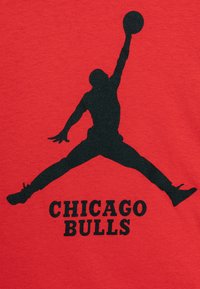 Camiseta de algodón roja con una silueta negra de un jugador de baloncesto saltando, con el texto "CHICAGO BULLS" en letras negras en negrita debajo.