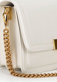 Sac à main en cuir blanc avec une bandoulière en chaîne dorée, de forme rectangulaire, bords cousus et un accent en matériel doré sur la fermeture à rabat.