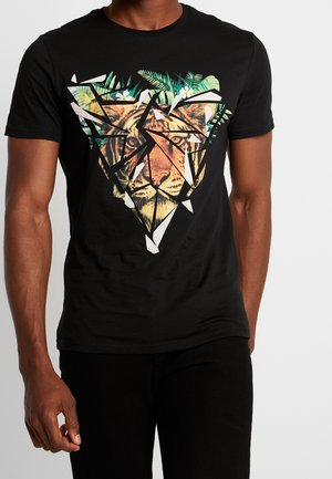 Mand iført sort t-shirt med fragmenteret geometrisk tigeransigt og tropiske blade grafik foran.