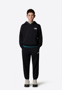 Conjunto de hoodie e calças pretas, feito de tecido macio. Apresenta um bolso frontal, detalhe azul na cintura e um logótipo no peito e na perna da calça.