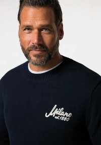Maglione a maglia blu navy con colletto rotondo a coste. Presenta un logo ricamato bianco "Milano est 1880" sul lato sinistro del petto.