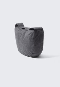 Borsa in tessuto grigio con superfice morbida e texture, forma rettangolare e una tracolla larga per il trasporto. Nessun hardware o pattern visibili.
