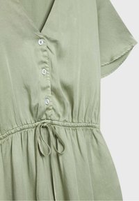 Robe vert clair avec manches courtes, boutonnée devant, col en V et taille réglable avec cordon.
