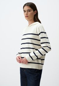 Hoodie-Pullover in Creme mit marineblauen horizontalen Streifen. Verfügt über gerippte Bündchen und Saum, einen lockeren Schnitt und eine weiche Stofftextur.