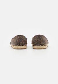 Mocassins en tissu brun avec un motif, semelle en corde de jute, bout arrondi et détails texturés le long des bords.