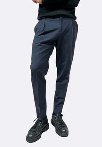 Pantaloni sartoriali blu navy realizzati in tessuto leggero, con vestibilità slim e tasche laterali, abbinati a sneakers nere chunky.