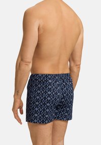 Pánské plavky s modrým diamantovým vzorem na tmavém pozadí. Elastický pas pro pohodlí a měkká textura.