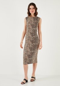 Leopard print fitted dress with a high neckline, sleeveless design, stretchy fabric, and knee-length hem, paired with black strappy sandals.