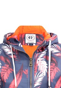 Floral-patterned jacket featuring a navy base with red and white leaf designs, an orange interior, front zipper, and drawstring hood.