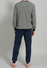 Camisa de manga larga en gris con un patrón texturizado, combinada con pantalones azul marino. Ambos tienen puños elásticos y un ajuste relajado.