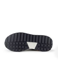 Semelle de chaussure en caoutchouc noir avec de profonds cannelures et motifs pour l'adhérence, présentant une pièce centrale blanche avec un logo.