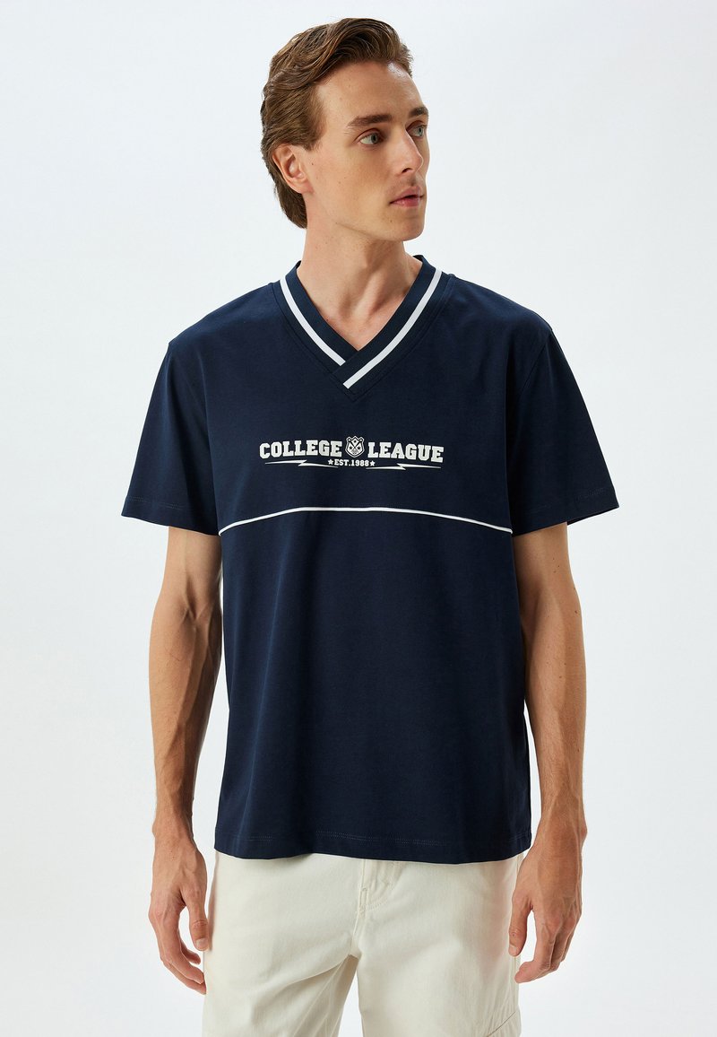Marineblå t-shirt med v-hals og hvidt læg, med teksten "COLLEGE LEAGUE EST. 1988" trykt i midten. Korte ærmer og blødt bomuldsstof.