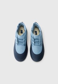 Une paire de chaussures d'hiver légères bleues et marines avec doublure en fourrure et lacets, vue d'en haut sur un fond blanc.