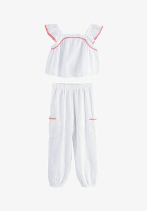 Witte katoenen tweedelige set met opengewerkte textuur. De top heeft ruffles aan de mouwen en een roze bies; de broek heeft een elastische tailleband en zakken.