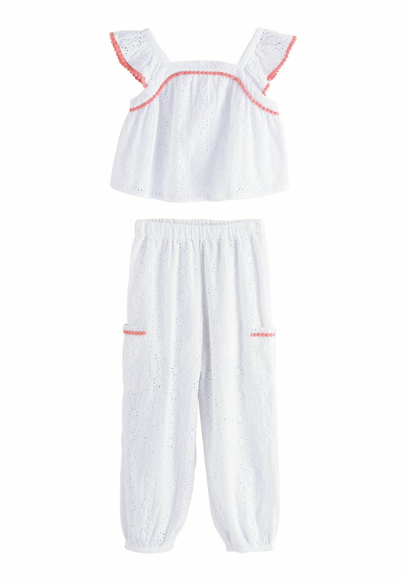 Hvid bomulds to-dels sæt med eyelet tekstur. Toppen har flæseærmer og pink kant; bukserne har elastisk liv og lommer.