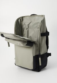 Rucksack aus hellgrauen und schwarzen Materialien; verfügt über ein geräumiges, offenes Hauptfach, eine vordere Reißverschlusstasche und verstellbare Träger.
