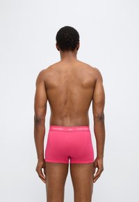 Ροζ ανδρικά εσώρουχα boxer με απαλό ύφασμα, ελαστική μέση με το λογότυπο "Calvin Klein" και εφαρμοστό σχεδιασμό, εμφανιζόμενα από πίσω.