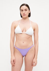 Ensemble de bikini comprenant un haut triangulaire blanc texturé avec des bretelles réglables et un bas taille basse lavande. Tissu lisse, design minimaliste.