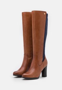 Brown leather knee-high boots with a navy fabric back, rounded toe, and a black block heel. Features a gold accent on the side.