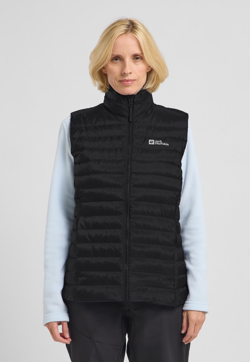 Gilet nero imbottito con colletto alto, chiusura a zip e motivi a cucitura orizzontale. Logo sul lato sinistro del petto. Indossato sopra una maglietta azzurra chiara.