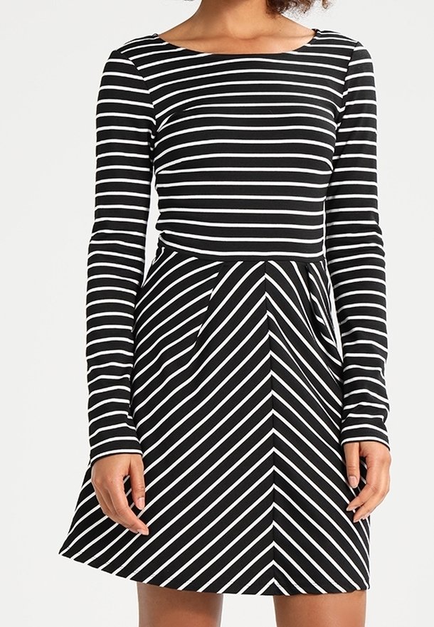 Robe à manches longues en rayures noires et blanches. Corsage ajusté avec une jupe évasée. Rayures horizontales en haut, passant à des rayures diagonales à la taille.