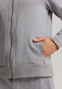 Felpa grigia con zip realizzata in morbido tessuto. Presenta una zip a lunghezza intera, tasche laterali e polsini e orlo a coste per un comfort extra.
