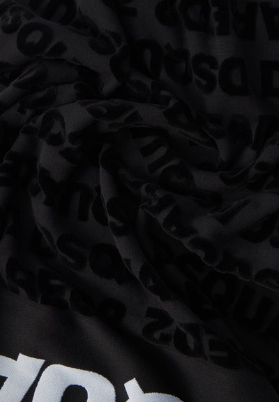 Μαύρο ύφασμα με απαλή υφή που διαθέτει ανάγλυφα μαύρα γράμματα διακοπτόμενα από έντονο άσπρο κείμενο, δημιουργώντας εφέ πολλαπλών επιπέδων σχεδίασης.