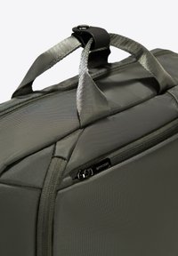 Grijze stoffen tas met een geprofileerd oppervlak, voorzien van handvatten aan de bovenkant en een ritszak aan de zijkant. Duurzaam materiaal met een hoekig ontwerp.