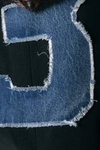 Must kits, millel on suur, kulunud teksapätk, mis on kujundatud numbrina 3. Pätk on vanutatud tekstuuriga ja sinise värviga.