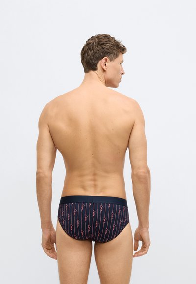 Tengerészkék úszónadrág piros „love” felirattal ismétlődő mintában. Vékony gumis derékrésszel és testhez simuló szabással készült, rugalmas anyagból.