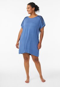 Abito azzurro con maniche corte e dettagli in pizzo sulle spalle, vestibilità rilassata e orlo leggermente più lungo sul retro.