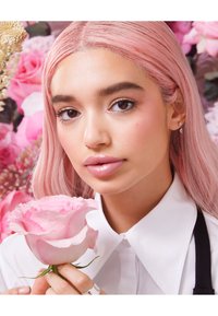 Portrait features a person with long, straight pink hair, holding a light pink rose. Wearing a white collared shirt, with silver jewelry accents.