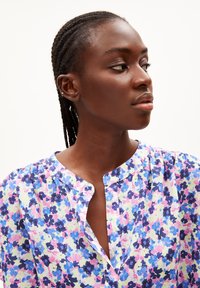 Blumenhemd mit einem mehrfarbigen Muster in Blau, Rosa und Lila. Leichter Stoff mit rundem Ausschnitt und Knopfdetails.