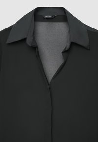 Blusa nera con colletto classico, realizzata in tessuto liscio e leggero con chiusura frontale con bottoni. Design semplice senza motivi visibili.