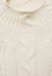 Pulover s kabelskim vzorcem v off-white barvi, ki ima rebrast okrogel ovratnik. Mehak tekstil z izrazitimi zavitimi vzorci po celotnem blagu.