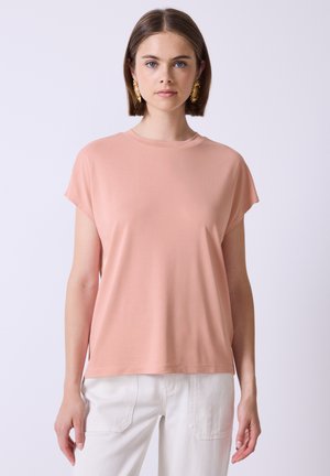 Weiches, rosa T-Shirt mit kurzen Ärmeln und lockerer Passform sowie Rundhalsausschnitt, gefertigt aus leichtem, glattem Stoff. Kombiniert mit weißen Hosen.