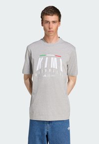 Grå bomulds t-shirt med korte ærmer, prydet med fed hvid tekst "KIMI ANTONELLI" og grønne/røde detaljer øverst. Casual pasform, rund halsdesign.