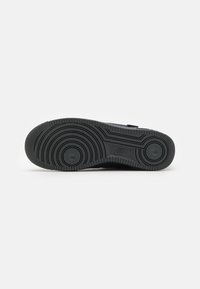 Talpa de cauciuc neagră cu un model de profil circular și elemente ridicate. Prezintă o textură netedă cu logo-ul Nike embosat aproape de călcâi.