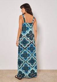 Maxi-jurk van stof met een zwart, turquoise en blauw bloemmotief. Vierkante schouderbanden, effen achterkant, lange uitvoering tot op de vloer.
