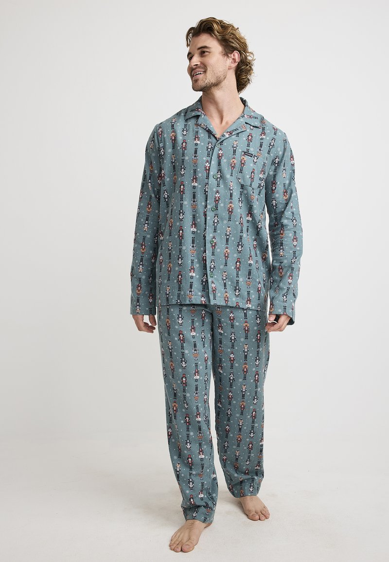 Men's cotton pajama set in teal, featuring a nutcracker pattern. Includes a button-up top and matching pants with an elastic waistband.