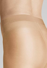 Durchsichtige hautfarbene Strumpfhosen mit glatter Oberfläche, ausgestattet mit einem breiten, strukturierten Bund für Komfort und Unterstützung, entworfen, um beim Tragen nahezu unsichtbar zu sein.