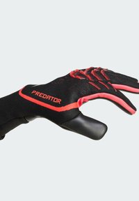 Black and red glove with textured fingers, reinforced fingertips, and a sleek design. Features "PREDATOR" logo on the wrist area.