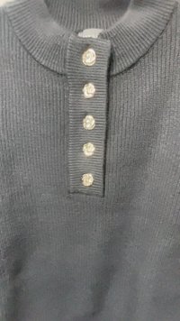 Maglione nero a coste con scollatura rotonda e cinque bottoni decorativi dorati sul fronte. Tessuto testurizzato con un design lavorato a maglia.