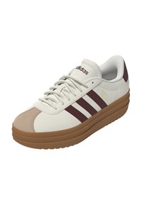 Scarpa sportiva bianca con strisce color bordeaux, punta beige e suola in gomma marrone chiaro. Presenta un esterno in pelle testurizzata e un colletto imbottito.