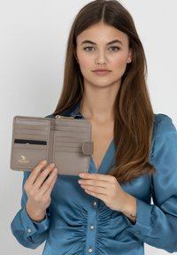 Gray leather wallet with multiple card slots, a zipper compartment, and a subtle logo design. Smooth texture and compact rectangular shape.