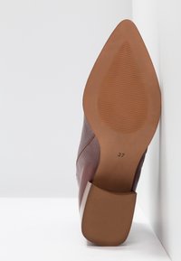 Chaussure en cuir marron à bout pointu avec un talon carré, affichée semelle vers le haut montrant la taille 37 sur une surface et un fond blancs.