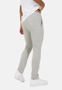 Szare dresy wykonane z miękkiego materiału, posiadające tapered design, kieszenie boczne i elastyczny pas. Obuwie: białe trampki.